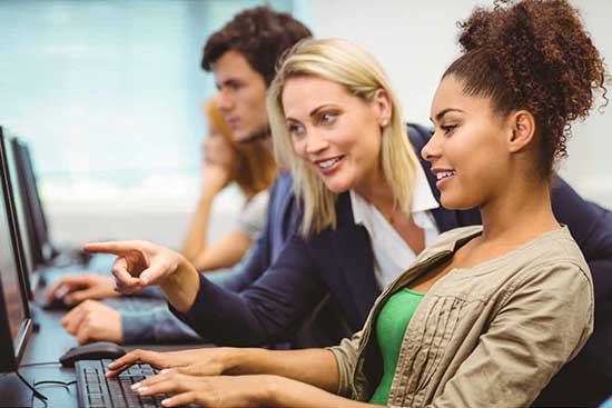 Teacher points to information on a student's desktop computer.