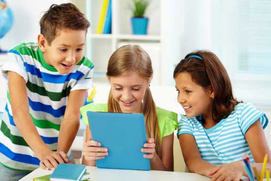 Three elementary students viewing a tablet computer.