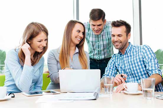 Four educators viewing laptop.